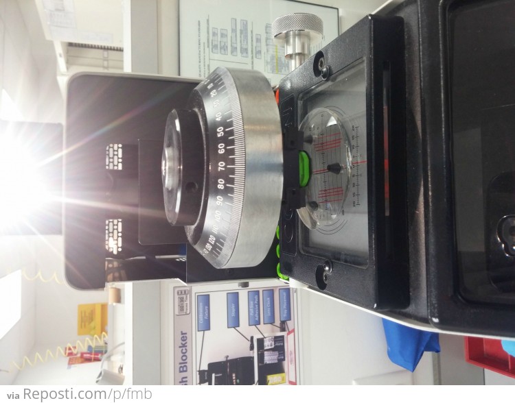 The arm swings over, drops down and attaches the block to the lens in the correct spot.
