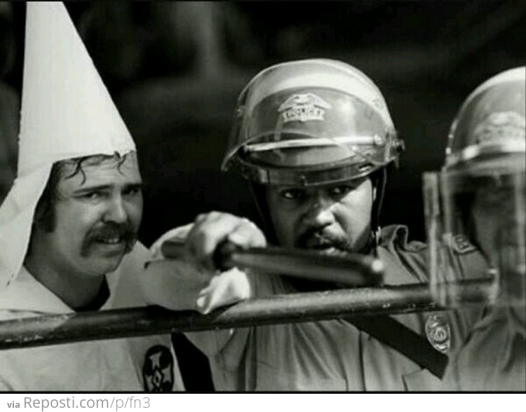 Black officer protecting KKK member from protesters, 1983